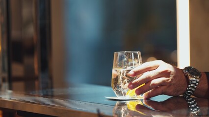 Closeup customer hand placing gin fizz or tonic drink with sliced orange at bar counter club greeting welcome guess waiting friend, refreshing beverage for pub and restaurant advertisement. Vinosity.