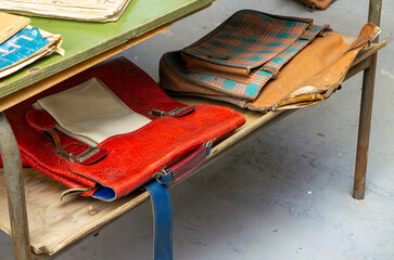 Old school satchels from the communist era lying on a metal bench. Characteristic colors, patterns,...