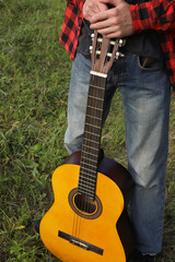 young guy in a red shirt with an acoustic guitar in nature