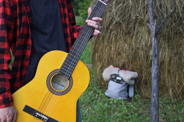 young guy in a red shirt with an acoustic guitar in nature