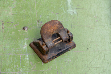 Rusty metal hole punch on a scratched green surface. Old office tool from the PRL era, showing...