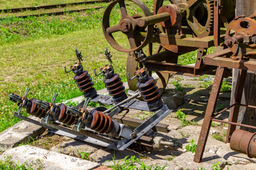 Vintage electrical insulators and rusty industrial machinery outdoors, set against green grass. Old...