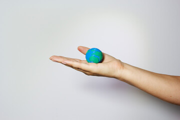 Hand presenting miniature Earth globe on open palm against neutral background, representing environmental care and responsibility. Environmental conservation concept. Humanitarian aid an global unity.