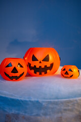 Three halloween pumpkin buckets sitting on dry ice creating spooky fog with blue background