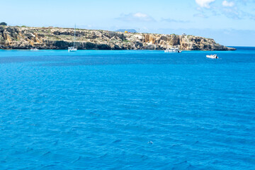 Fototapeta premium Boat trip and view on coastline of Favignana island with shallow bays with clear turquoise water, tuff rocks, abandoned quarries, caves, Egadi Islands near Sicily, Italy