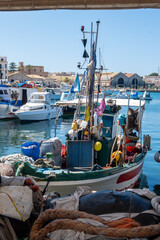 Little traditional colourful fishing boats in Favignana island's harbour, near Sicily, tourists...