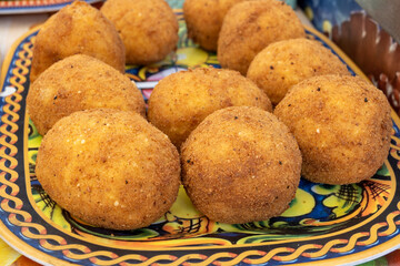 Arancini Sicilian, deep-fried rice balls made with risotto, filled with ingredients mozzarella, ragu, peas, coated in breadcrumbs fried to crispy, brown on market in Palermo, Sicily
