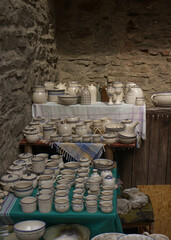 Handmade ceramic mugs, bowls and pots at the castle fair. Period ceramic dishes on a stand. Replicas of ancient ceramic objects.