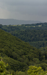 Summer cloudy sky over alpine landscape. Dense forest cover. Summer sky before an approaching storm.