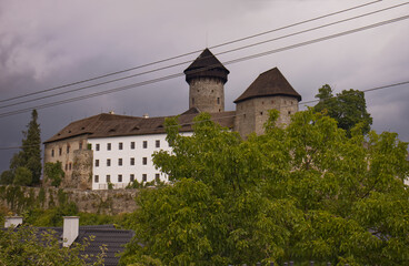Dramatic sky over stone castle. Stormy gray clouds. Large stone castle. Traveling around the sights of the Czech Republic. travel during summer vacation. Trees and nature around the castle.