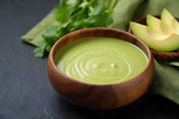 Creamy Avocado Soup: Showcase Vibrant Green, Rustic Wooden Bowl, Fresh Cilantro Garnish.
