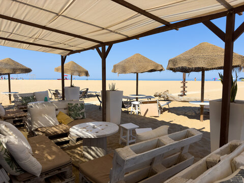 Strandbereich mit Liegen, Sonnenschirmen und &uuml;berdachter Lounge: Komfort, Erholung, Urlaubserlebnis und stilvolle Strandatmosph&auml;re f&uuml;r entspannte Stunden am Meer genie&szlig;en