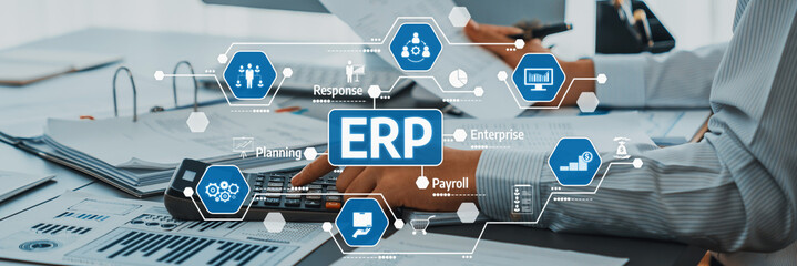 A business professional engages with enterprise resource planning data on an office desk filled...