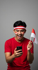 Excited young man in red shirt, Indonesian flag, and face paint, looking at a phone.