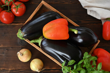 still life in rustic style with bell peppers, eggplants and tomatoes and basil