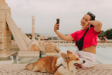 Young girl with Corgi recording video on phone share via app her travel vacation. Gen Z influencer...