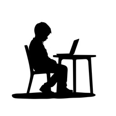 Boy sitting at desk using laptop in silhouette  
