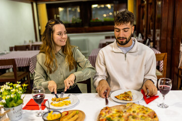 Young Couple Cutting Pizza and Fried Chicken on Romantic Date