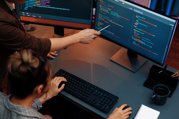 Top view of IT developers discussing with point to intelligent website development coder system...