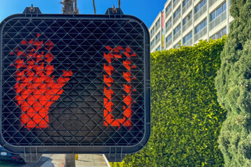 Close-up of a red pedestrian signal with a raised hand and countdown timer down to zero at a crosswalk in Santa Monica, California, USA