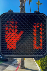 Close-up of a red pedestrian signal with a raised hand and countdown timer down to zero at a...