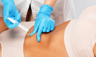 Aesthetic cosmetologist makes lipolytic injections to burn fat on the body of a woman. Female...