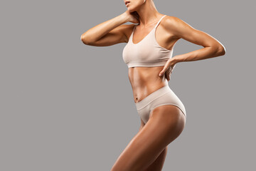 A slender swarthy woman in beige underwear on a dark background. Healthy lifestyle, sport and diet.