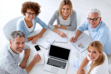 Top view of diverse team meeting around laptop with reports – teamwork and office collaboration concept