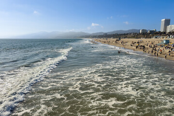 Scenic view of coastline with waves and people enjoying beach life in Santa Monica Beach against blue sky