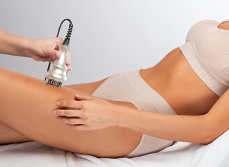 The doctor does the Rf lifting procedure on the legs, buttocks and hips of a woman in a beauty...