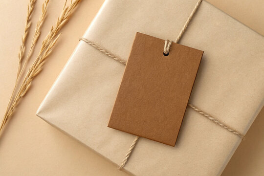Minimalist gift presentation features a parcel tied with string and a blank brown paper tag alongside dried wheat