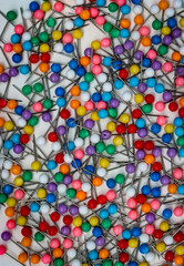 Multiple colorful push pins scattered over a white background.