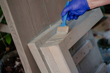 The process of gray painting a wooden step. A woman paints a wooden product. 