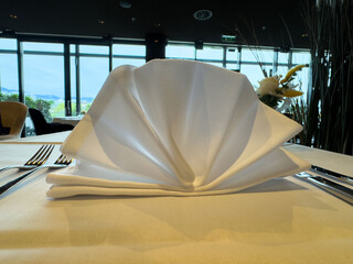 Elegant table setting with folded white napkin in fine dining restaurant