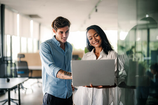 Two happy diverse multiethnic business team people working, talking in corporate office