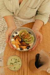 Close-up of female hands holding a plate. Granola with fresh fruit and yoghurt. A healthy natural...