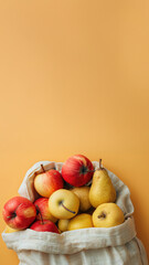 Fabric canvas bag with ripe yellow pears and apples, biodegradable materials, eco friendly, farm fruit harvest. Vertical mockup with fruits and copy space for text on orange background