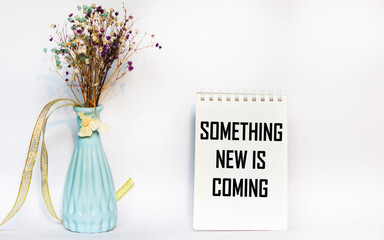 The message "Something new is coming" is written on a notepad page on a white background.
