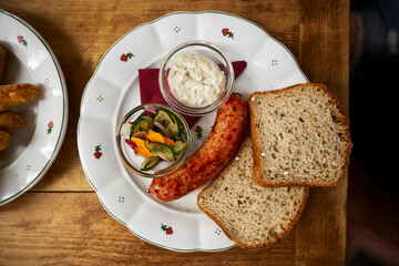 Rustic breakfast with sausage, horseradish, salad and bread - top view on wooden table