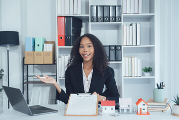 Real Estate Agent in Her Office: A professional, confident real estate agent sits at her desk,...