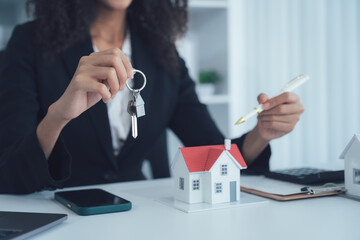 Property Keys and Expertise: An image of a real estate agent holding house keys and a pen while a...