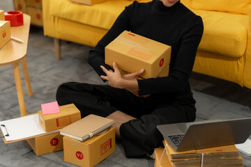 Online Business Startup: A woman is surrounded by packages and a laptop, embodying the hustle of a...
