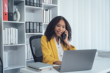 Modern Professional in Workspace: A stylish business woman engages in a phone conversation at her...