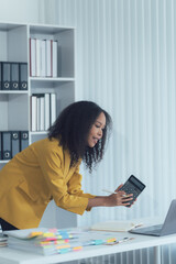 Accountant at Work: A dedicated accountant in a yellow blazer intently uses a calculator amidst...