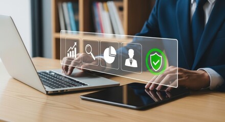 A person using a laptop and tablet with business icons displayed on a transparent screen overlaying them