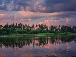 river view with clouds above forest and reflections in water in twilight with copy space