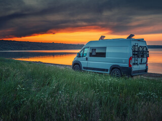 white van on sea shore in deep twilight with beautiful sunset sky