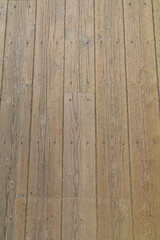 Fototapeta premium Close-up of aged wooden deck boards with visible grain, cracks, and texture. Ideal for backgrounds, textures, or rustic design elements