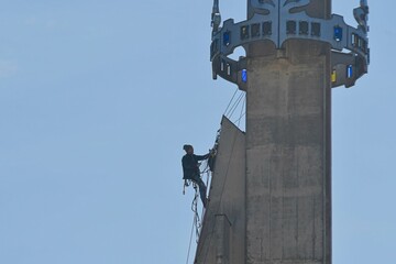 A craftsman repairs the tower of a modern church. A tinsmith repairs the tower of a modern building. The concept of working at heights and work safety