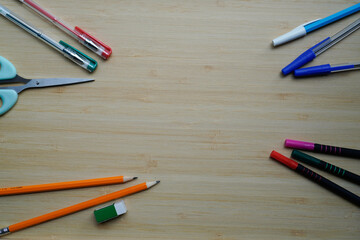 Top view of colorful pens and pencils on wooden background